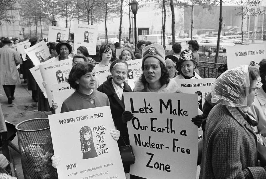 Coretta Scott King protesting on the street, holding a sign that says "Let's make our Earth a nuclear-free zone"