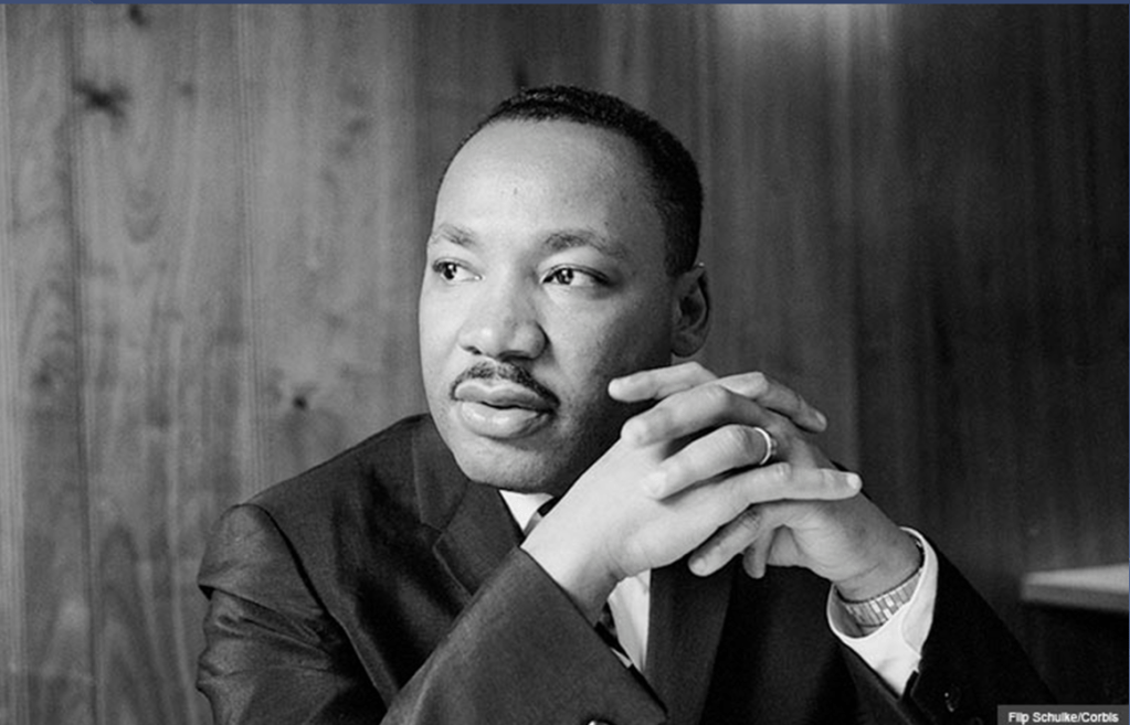 Black and white image of Martin Luther King Jr. sitting in an office.