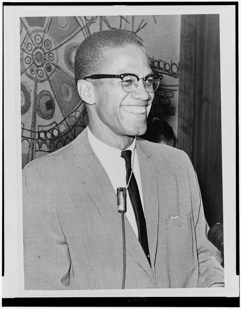 Black and white photo of a smiling Malcolm X